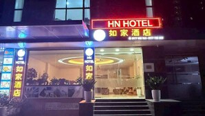 Ein Hotel mit einem auffälligen Neonzeichen mit der Aufschrift "HN HOTEL" und einem kleineren Schild in einer Landessprache.