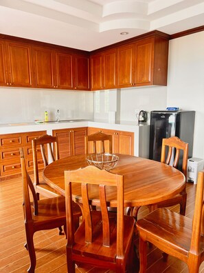 A modern kitchen with wooden cabinets, a round dining table, and a refrigerator. - Sunset Ocean View 3-king bed Villa Directly Above Patong (Phuket)