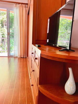 A room with a wooden cabinet, a television, and a vase on a shelf. - Sunset Ocean View 3-king bed Villa Directly Above Patong (Phuket)