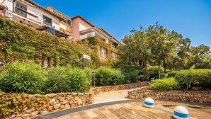 A paved pathway with stone bollards, a stone wall, and lush greenery. - La Terrazza Segreta (Olbia)