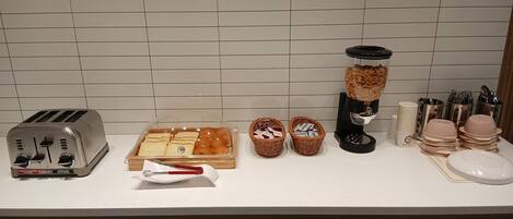 A kitchen counter with a toaster, a bread box, a coffee maker, and various utensils and dishes.