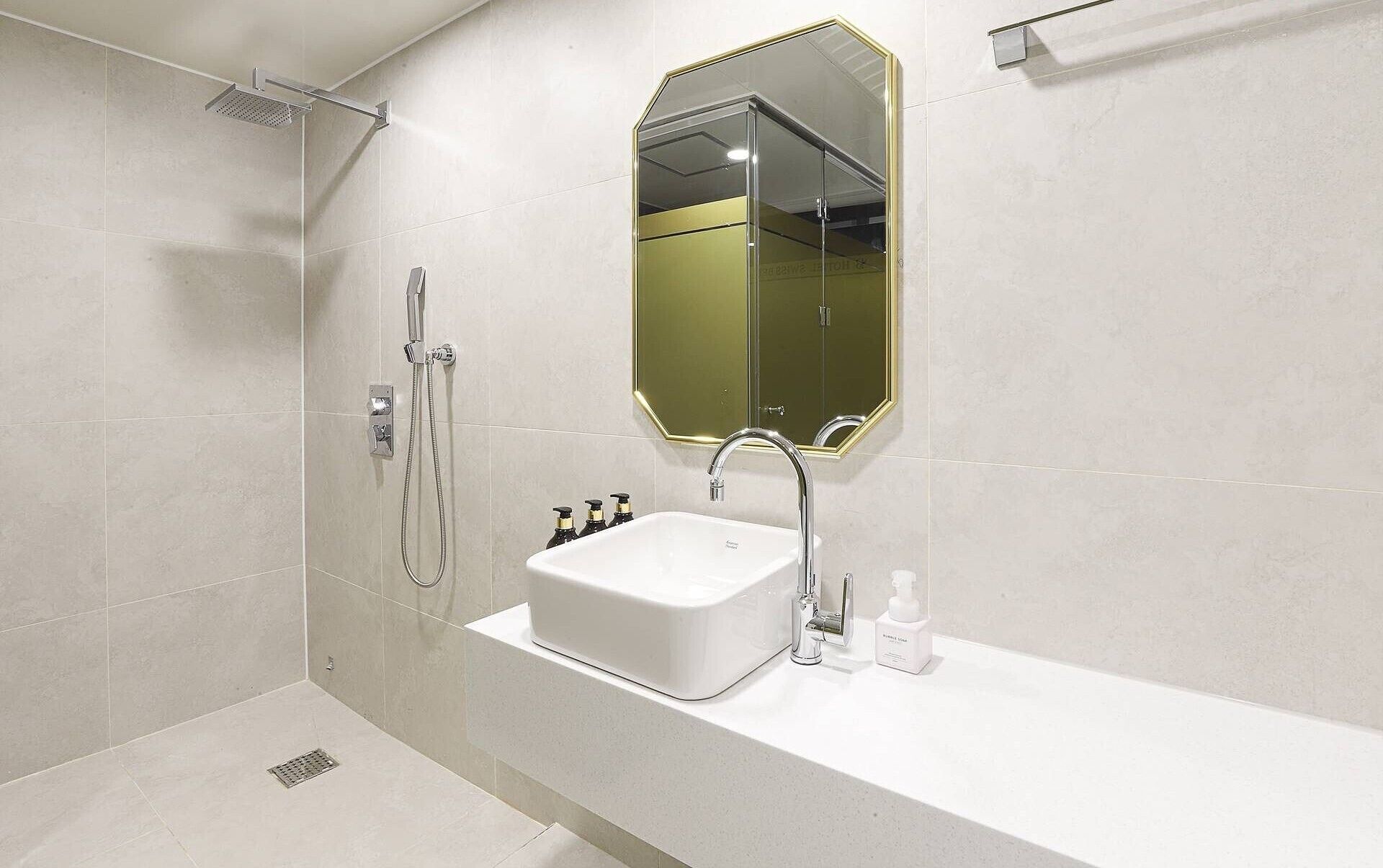 A modern bathroom with a shower, a sink, and a mirror.