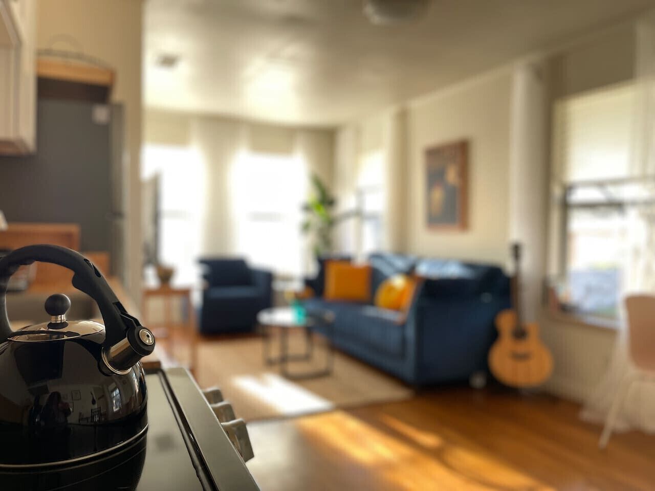 Ein modernes Wohnzimmer mit einer Couch, einer Gitarre und einem Wasserkocher auf einem Tisch.