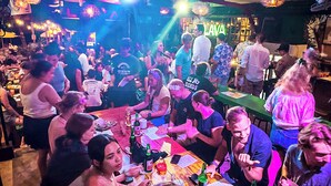 Un bar concurrido con gente sentada en mesas, algunas sosteniendo bebidas.