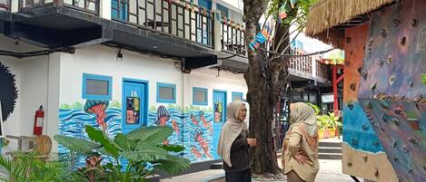 A courtyard with a ping pong table, a climbing wall, and a mural on the building.