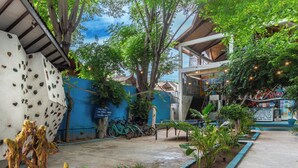 Un patio con una pared azul, un árbol y un edificio con un letrero que dice 'KUCHEN'.
