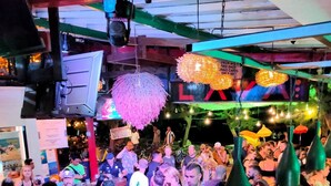 Un bar concurrido donde la gente conversa y bebe.