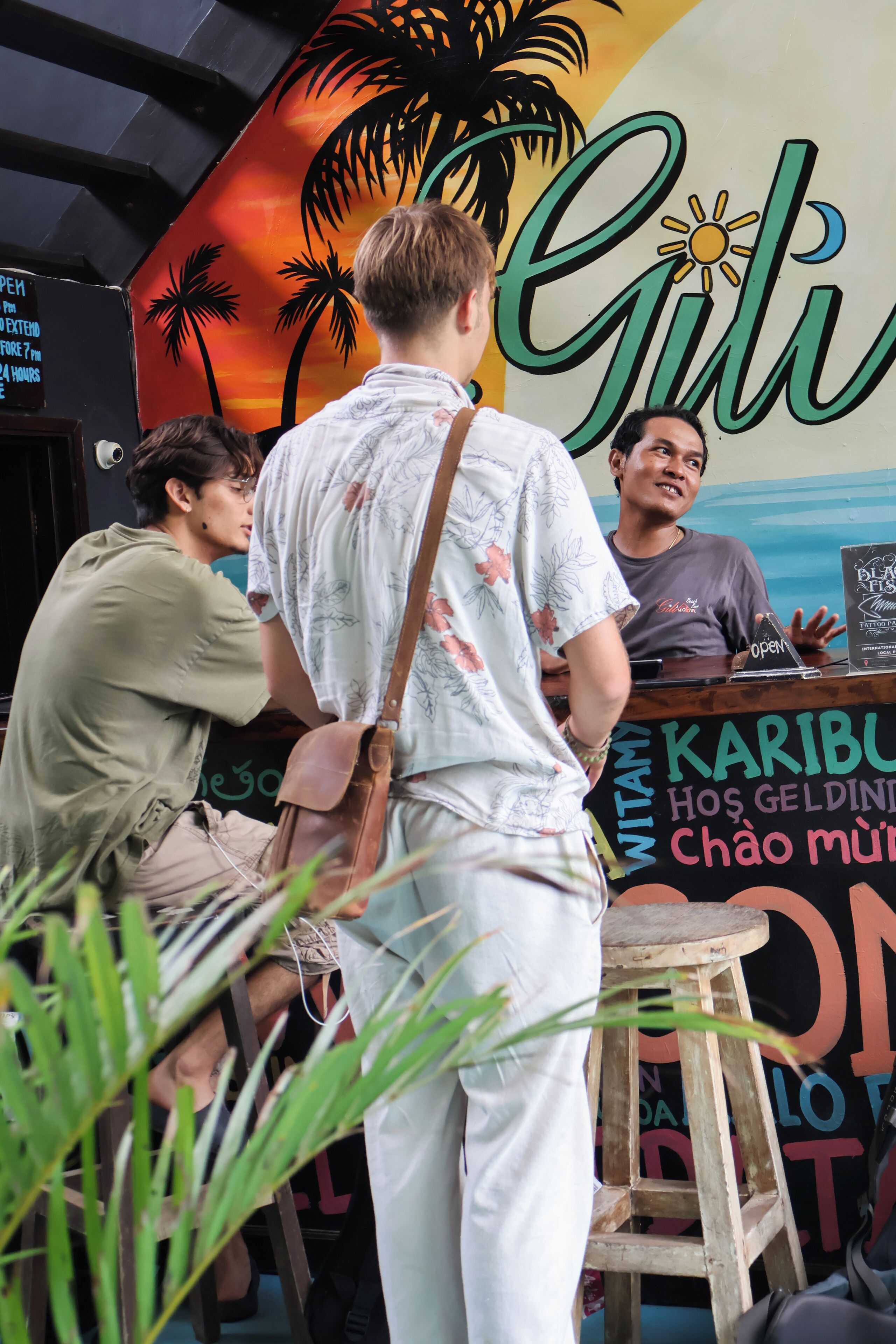A person standing at a counter with a sign that reads "Karibu" and "Gili".