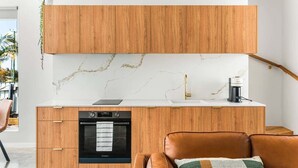 Una cocina moderna con armarios de madera, salpicadero de mármol y horno empotrado.