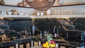 Una cocina moderna con un salpicadero de mármol negro, un microondas integrado y una variedad de electrodomésticos.