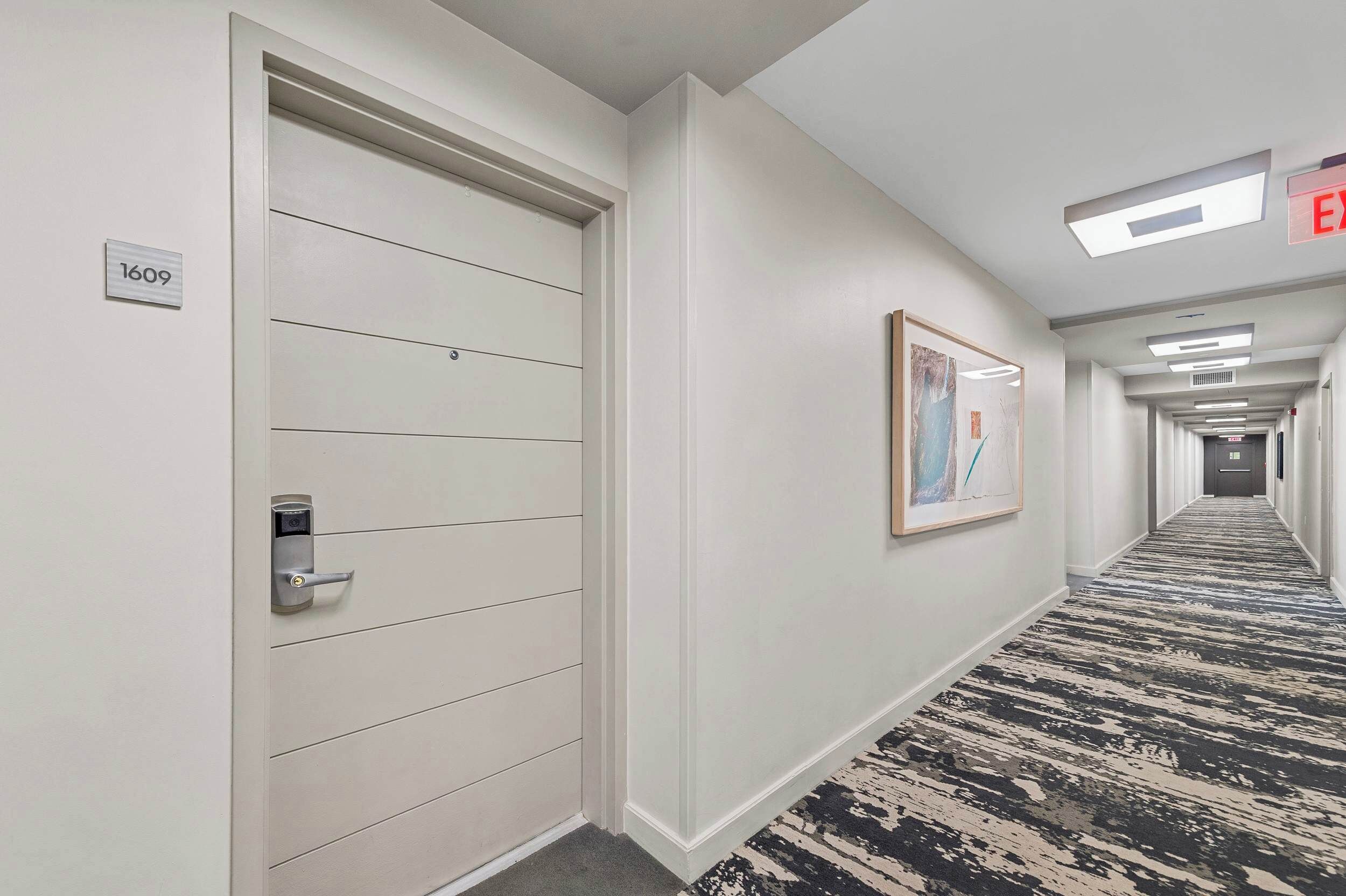 A hotel hallway with a door marked "1609", a framed artwork on the wall, and a patterned carpet.