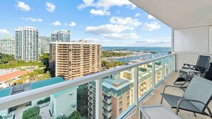 A balcony with a view of a cityscape, including high-rise buildings and a body of water. - ARYA Luxury Adjoining Suites Ocean View (Miami)