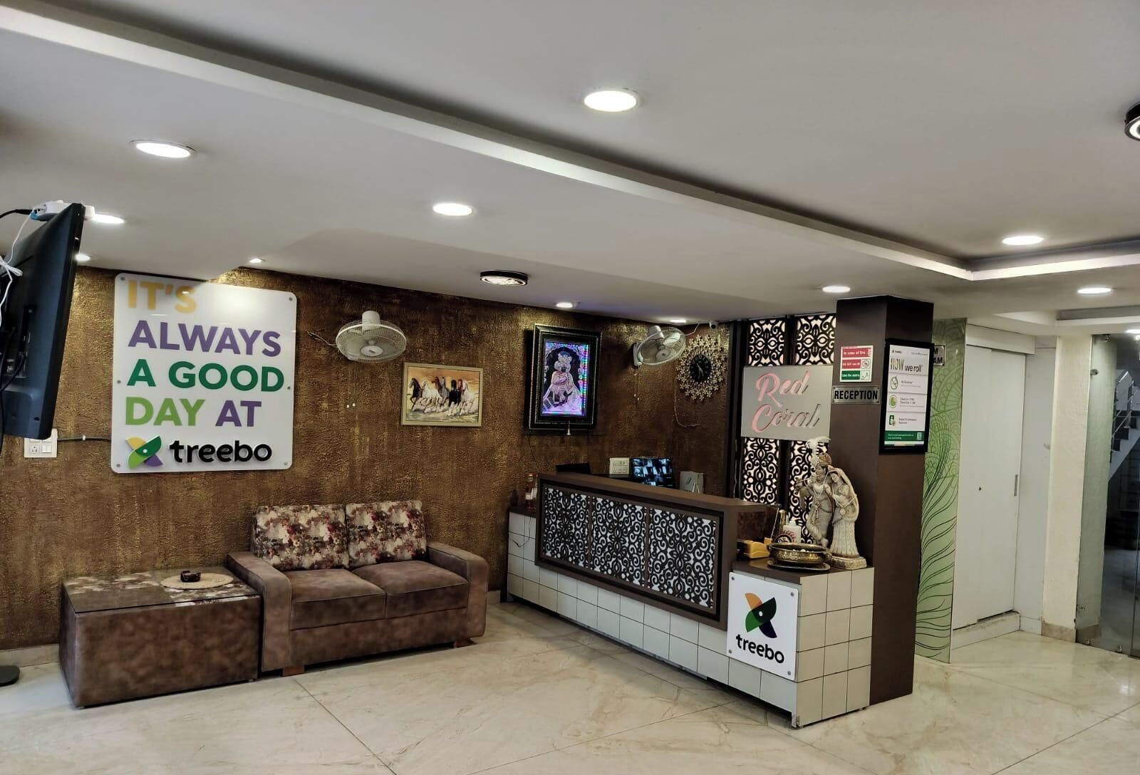 A reception area with a couch, a reception desk, a TV, and a sign that says "It's always a good day at treebo."