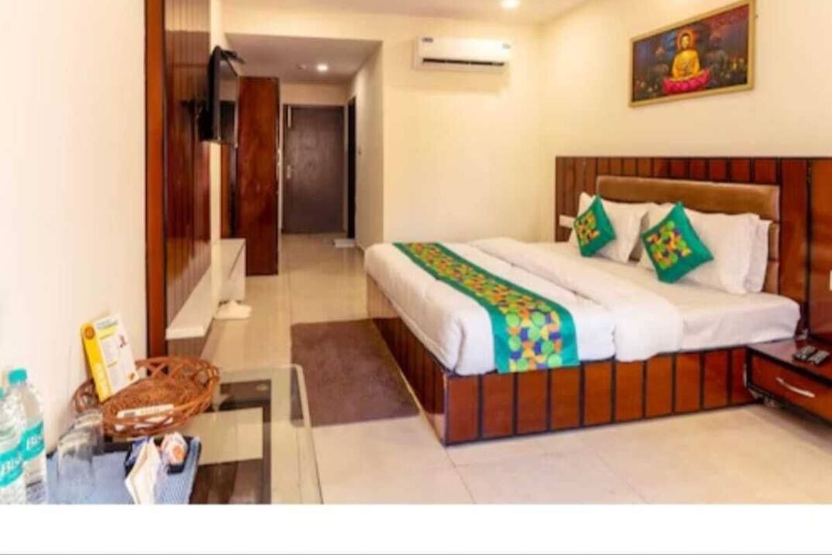 Ein Hotelzimmer mit einem Bett, einem Nachttisch, einer Wand-Klimaanlage, einem Deckenventilator und einem Bild an der Wand.