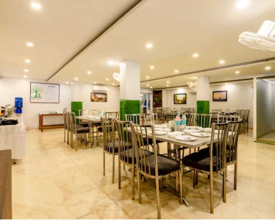 A spacious dining area with multiple tables and chairs, well-lit with ceiling lights, and a clean, modern design.