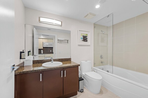 Un baño moderno con lavamanos, espejo, tocador, inodoro y bañera.