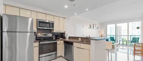 A modern kitchen with stainless steel appliances, a dishwasher, and a dining area with a balcony view.