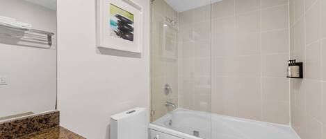 Ein modernes Badezimmer mit Toilette, einer Arbeitsplatte aus Granit, einer Badewanne und einer Duschkabine aus Glas.