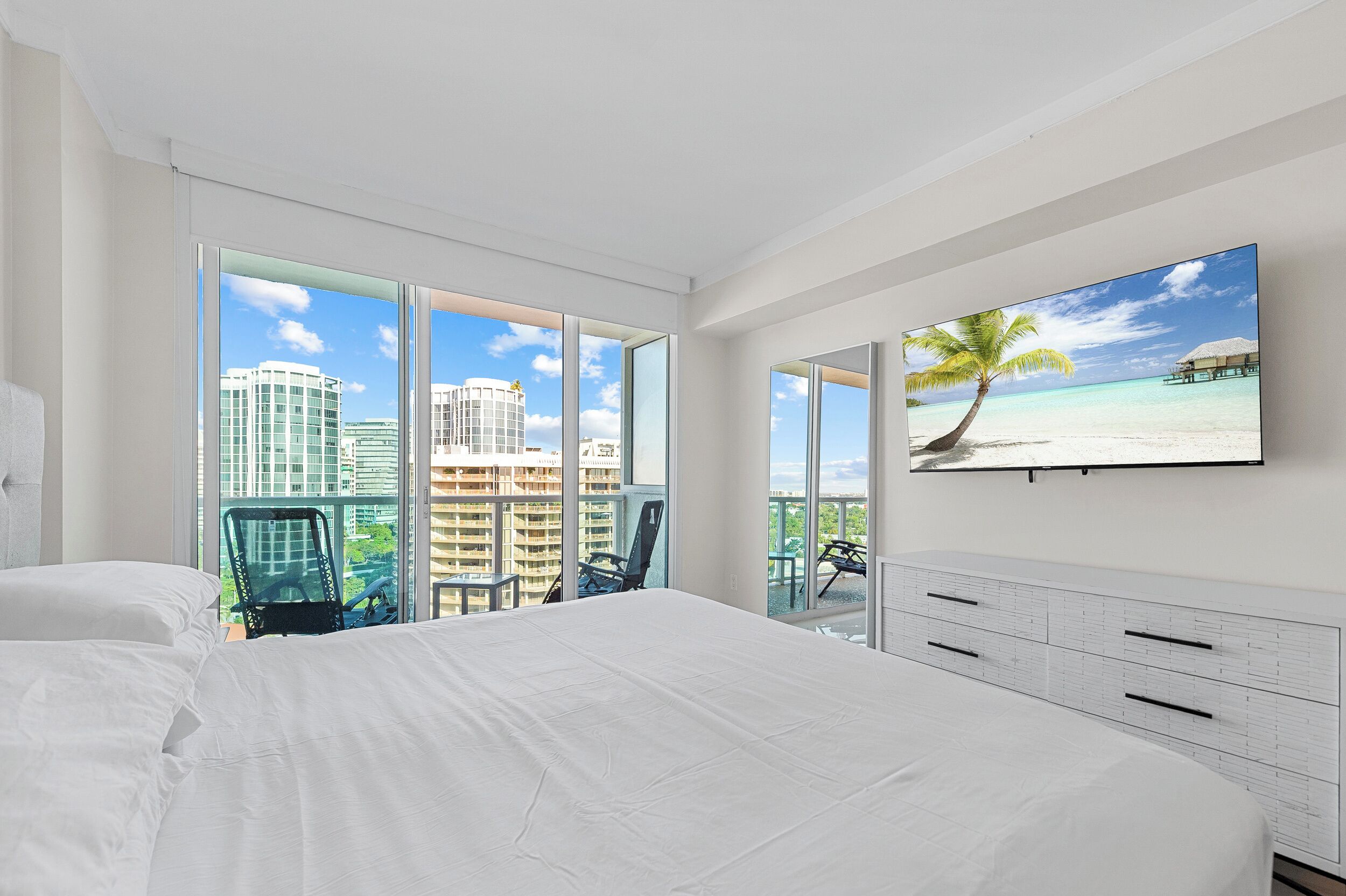 Ein Hotelzimmer mit einem großen Bett, einem Balkon mit Sitzgelegenheiten und Blick auf die Stadt.