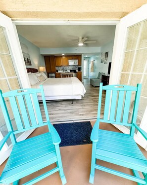 A bedroom with a bed, a kitchenette, and a bathroom visible through an open door. - Studio King Sunset at Beso Del Sol with Pool & Hot Tub (Dunedin)
