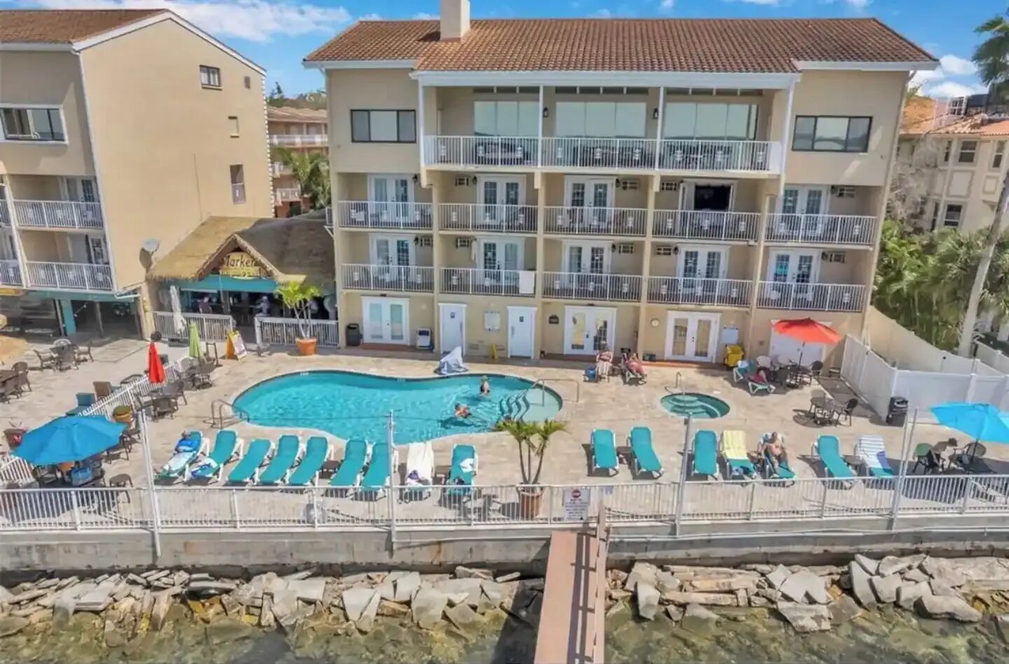 A multi-story hotel with a pool area, including sun loungers and a smaller circular pool.