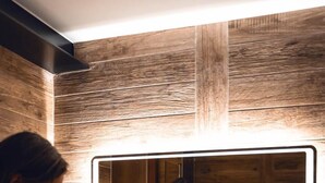 Un baño con pared de madera, un espejo grande y un lavamanos de piedra.