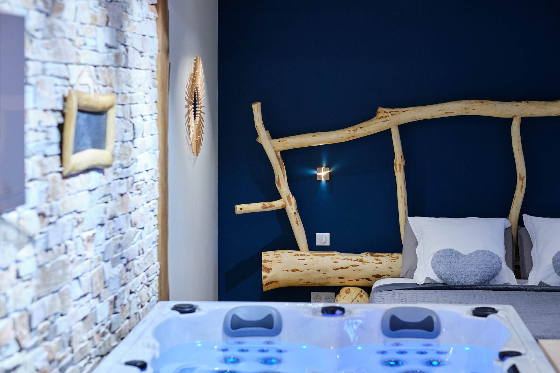 A bedroom with a stone wall, a wooden headboard, and a massage table.