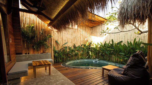 Una terraza de madera con un jacuzzi, zona de estar y paredes de bambú.