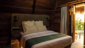 Una habitación de madera con una cama, una mesita de noche y una ventana.
