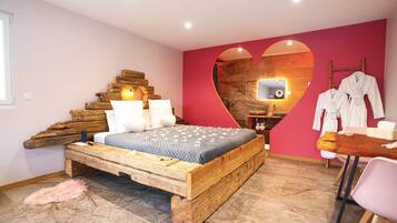 A bedroom with a wooden bed, a heart-shaped mirror, and a small table with towels.