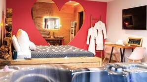A modern hotel room with a heart-shaped wall design, a bed, a desk, and a hot tub. - Loft Bisous Sucré - Romantic Suite & Private Jacuzzi (CARSPACH)