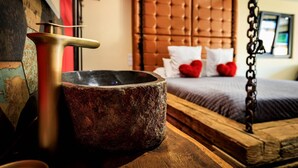 A rustic wooden bed with a tufted headboard, a stone basin, and a brass faucet. - Loft Olé-Olé - Erotic Love Room & Barrel Sauna (CARSPACH)