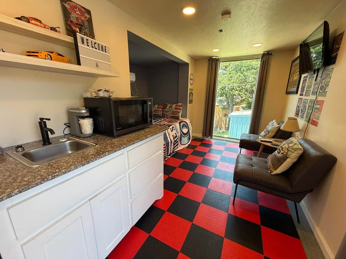 A compact kitchen with a sink, microwave, and a welcome sign.