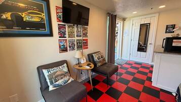 A room with two grey sofas, a small table, a wall-mounted TV, and a red and black checkered floor.