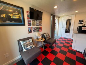 A room with two grey sofas, a small table, a wall-mounted TV, and a red and black checkered floor. - KBPPE Rooftop View@InnHabit—Family & Couples Slp 8 (Medicine Park)