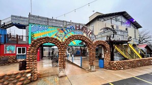 A building with a colorful mural, a staircase, and a unique sculpture made of nuts. - KBPPE Rooftop View@InnHabit—Family & Couples Slp 8 (Medicine Park)