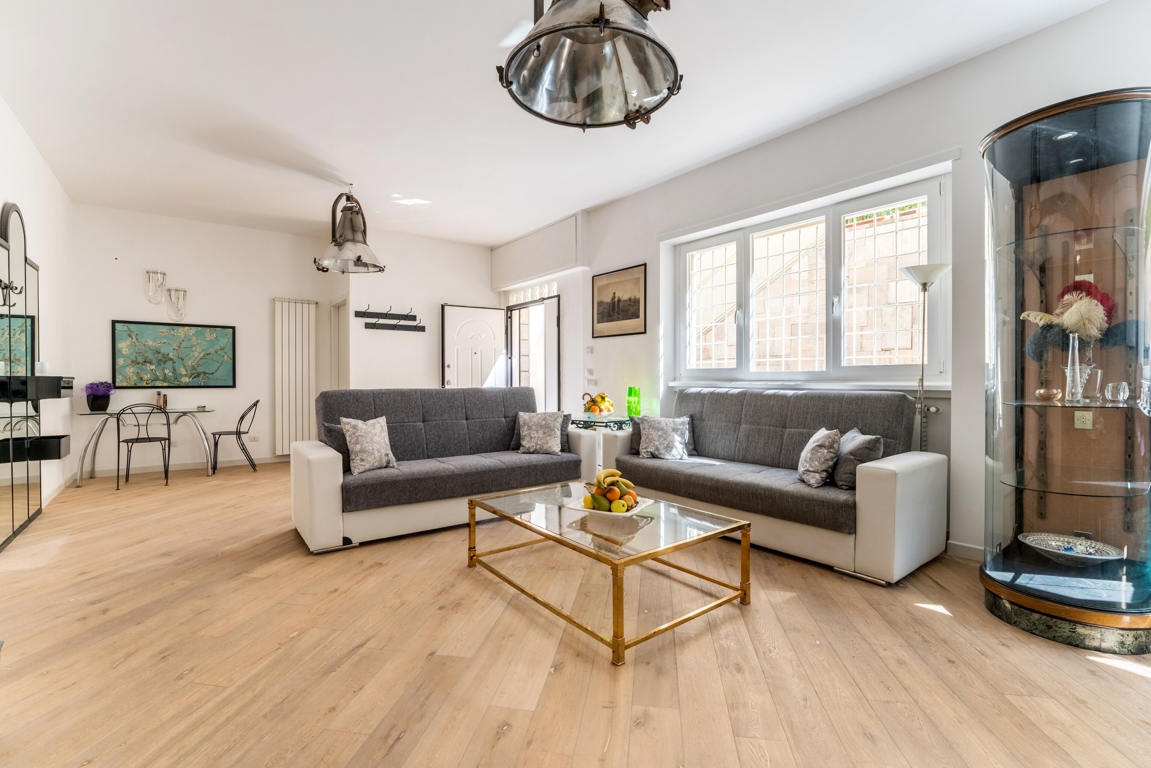 A spacious living area with two sofas, a glass coffee table, and a glass cabinet.