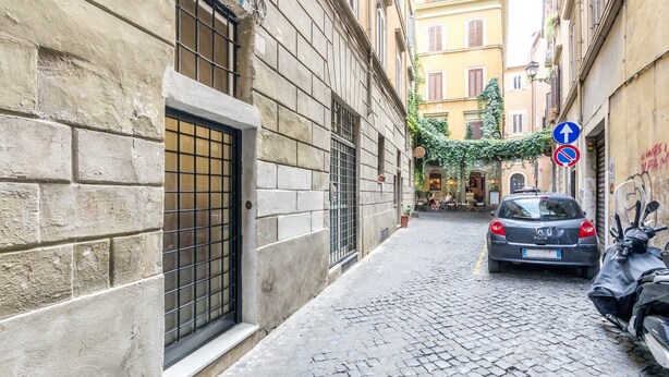 Une ruelle étroite pavée, avec une voiture garée et une moto sur le côté droit.