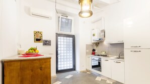 Une cuisine moderne avec des meubles blancs, un plan de travail en bois, un four encastré et un évier en acier inoxydable.