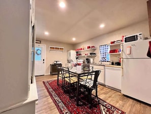 A compact kitchen with a dining table, chairs, a microwave, and a refrigerator.