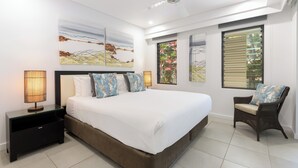 Une chambre à coucher moderne, dotée d’un grand lit, d’une table de chevet, d’une chaise et d’œuvres d’art accrochées aux murs.