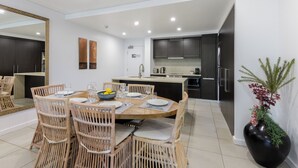 Un espace repas moderne avec une table ronde, des chaises en osier et un grand miroir.