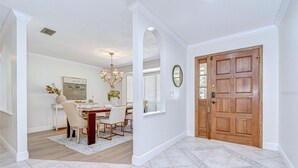 A dining area with a wooden table and chairs, a chandelier, and a window with blinds. - Spacious 4-bedroom house in quaint Tampa with AC (Tampa)