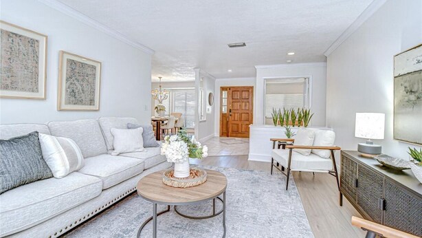 A spacious living room with a sofa, coffee table, and chairs. There is a dining area in the background with a table and chairs. - Spacious 4-bedroom house in quaint Tampa with AC (Tampa)