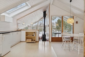 A modern kitchen with white cabinets, a wooden countertop, and a skylight.