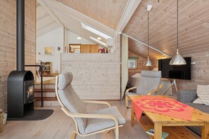 A cozy interior with a fireplace, seating area, and a TV mounted on the wall. - Cozy holiday home close to beach and nature (Nykøbing Sj)