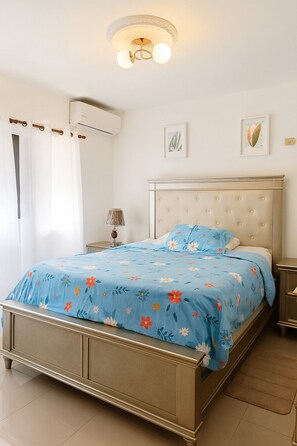 A bedroom with a bed, a nightstand, a lamp, and a ceiling light fixture.