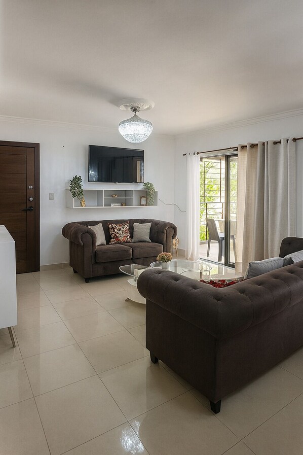 A modern living room with a sofa, a coffee table, and a TV mounted on the wall.