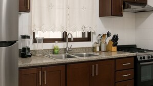 Una cucina moderna con mobili marroni, elettrodomestici in acciaio inossidabile, un lavello a due vasche e un piano cottura.