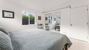 Un dormitorio con una cama grande, un armario con puerta corredera y una ventana con persianas.